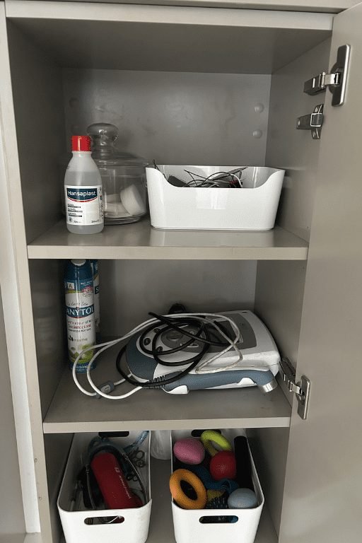 Étagère de rangement contenant un appareil d'électrothérapie, des électrodes et des produits d'hygiène